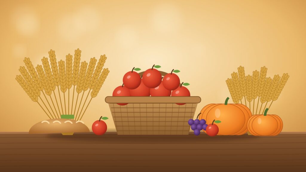 Erntekorb mit Äpfeln, Kürbissen, Brot und Getreidegarben auf einem Holztisch